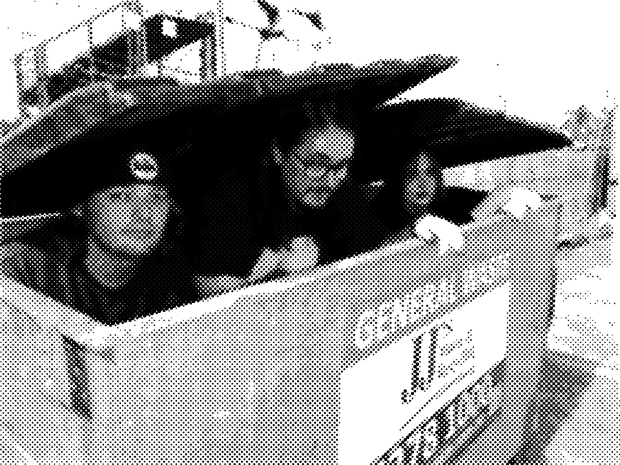 The three band members peering out of a General Waste skip bin with the lid propped open