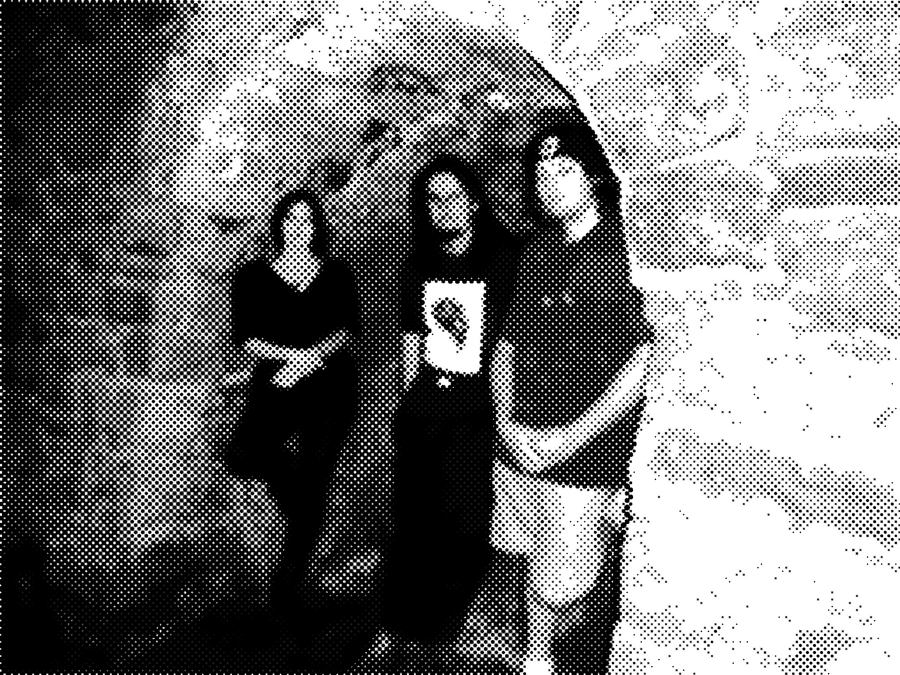 The three band members leaning against the wall of an old sandstone archway
